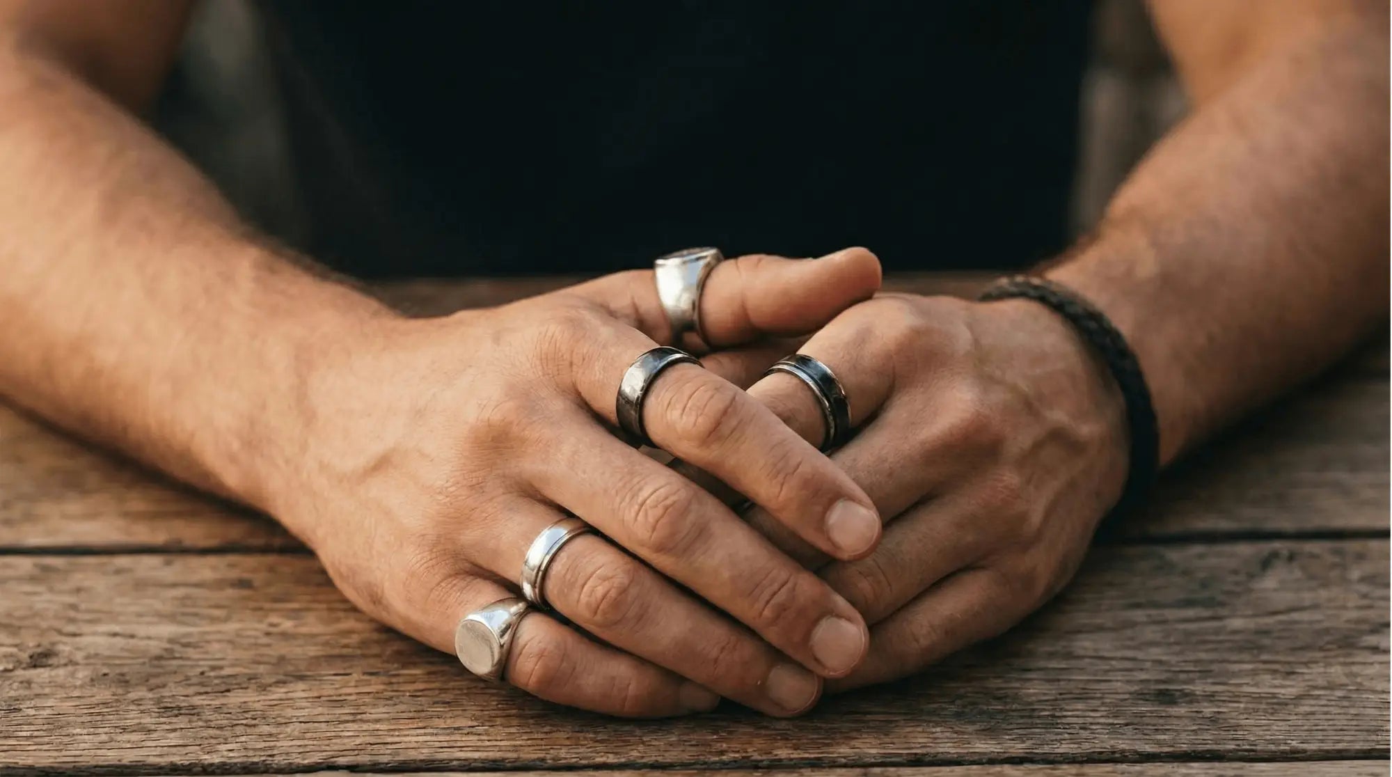 Une collection de bagues aux tons argentés avec des largeurs et des designs variés, incluant une avec un cadran rectangulaire.