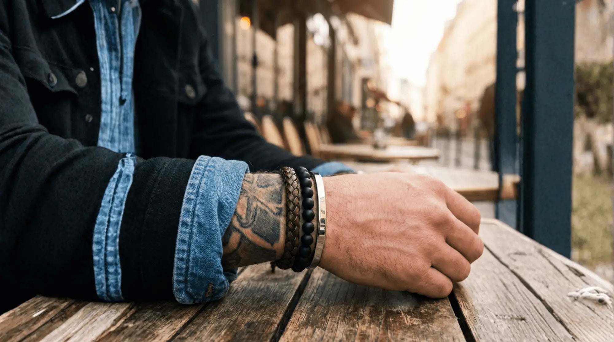 Bracelet perlé noir avec un bracelet métallique argenté porté au poignet.