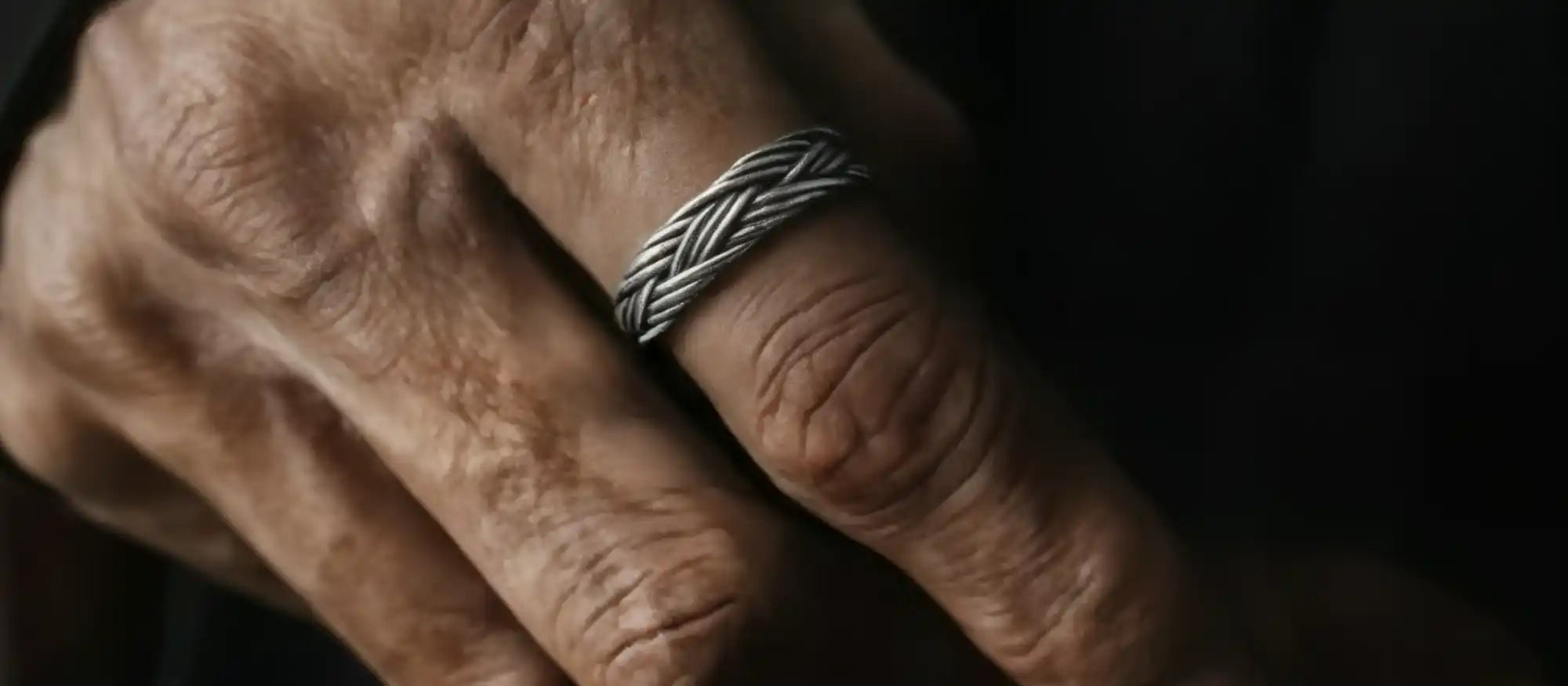 Une bague tressée en argent sur une main vieillie.