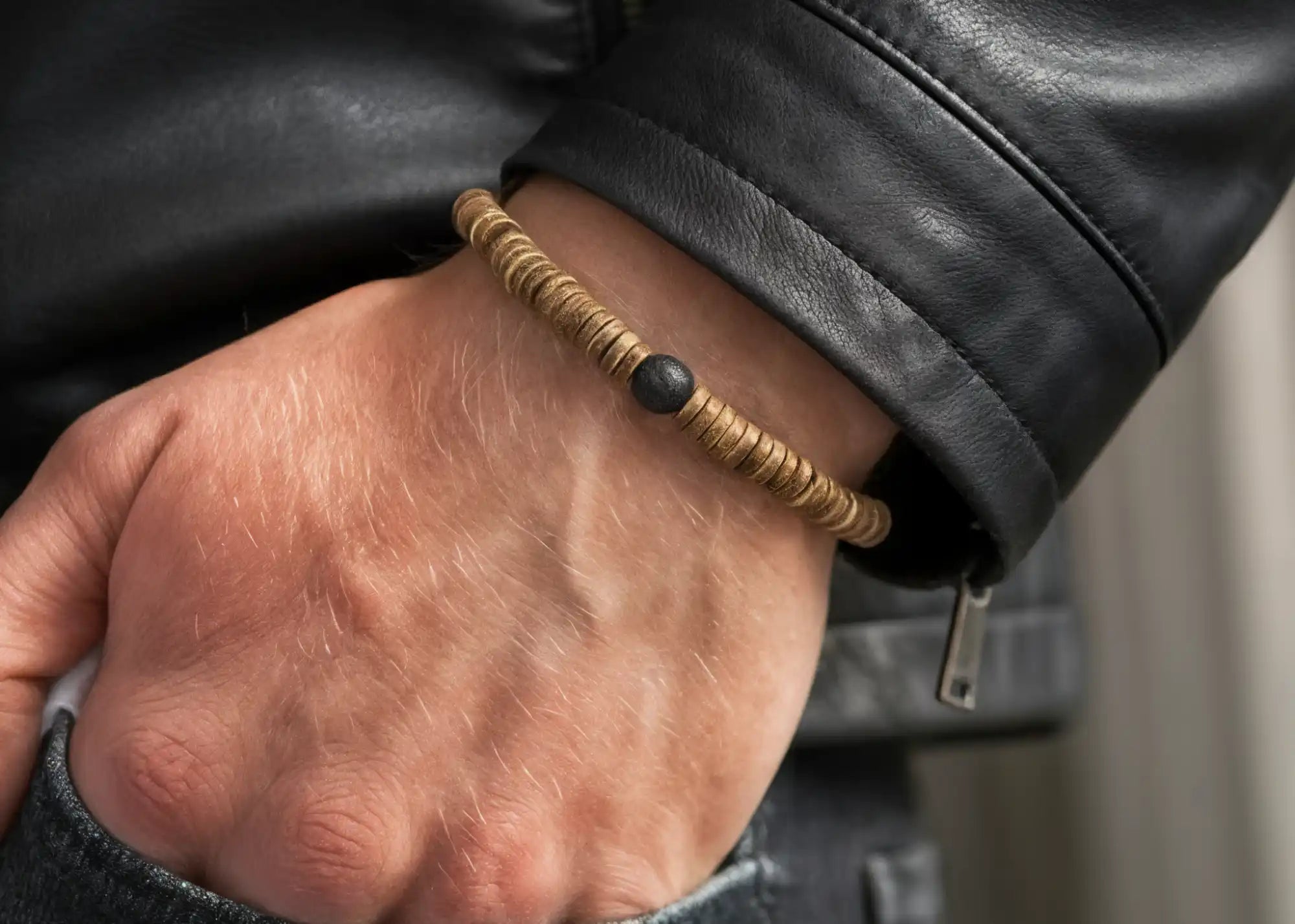 Le poignet d'un homme portant un bracelet en perles de bois à une seule rangée avec une perle centrale noire.