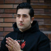 Un jeune homme portant un hoodie noir et une bague en or.