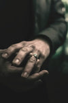 Les mains d'une personne jointes, avec une bague détaillée sur un doigt.