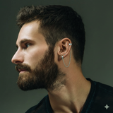 Un homme brun porte  des ear cuff avec chaine au style punk argentée