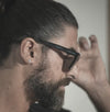 Un homme avec une barbe et des lunettes, portant une boucle d'oreille.