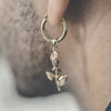 Une boucle d'oreille en or avec un pendentif en forme de rose suspendu.